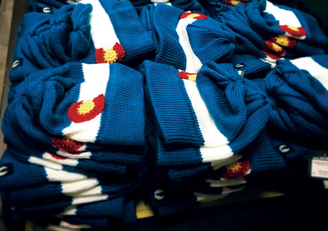 A pile of snow hats with the Colorado C on a white stripe surrounded by blue