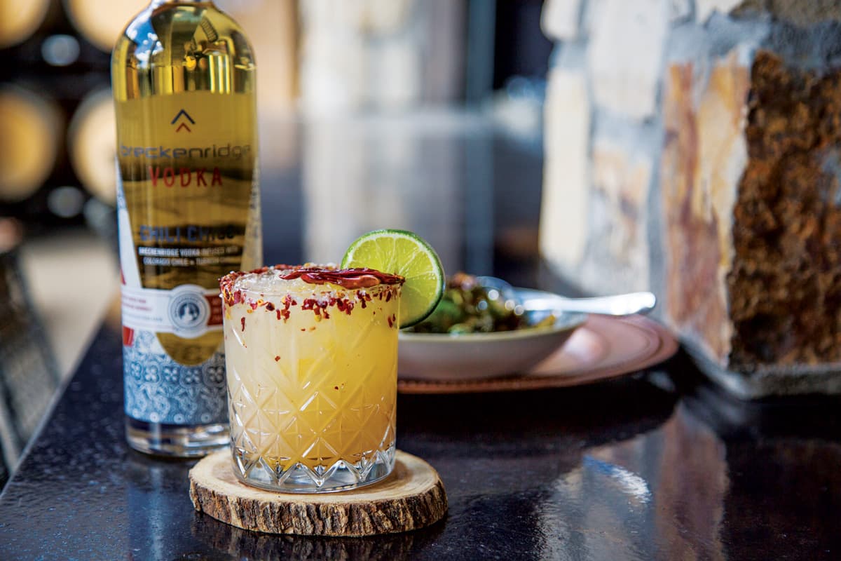 A spice-rimmed margarita and bottle of tequila on a restaurant table