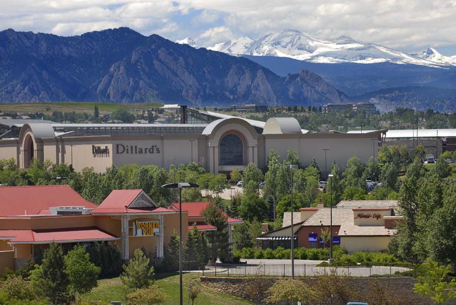 The Dillard's store at Flatiron Crossing mall sits under the Front Range mountains with lots of white clouds above.