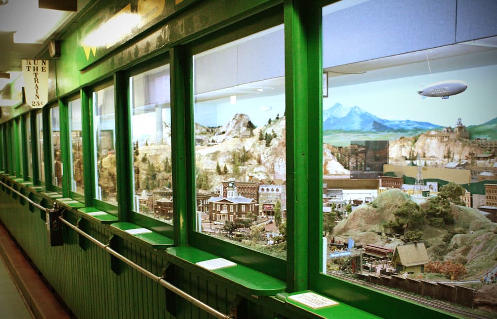 A tiny Denver HO Model Railroad is displayed inside a green-painted train car