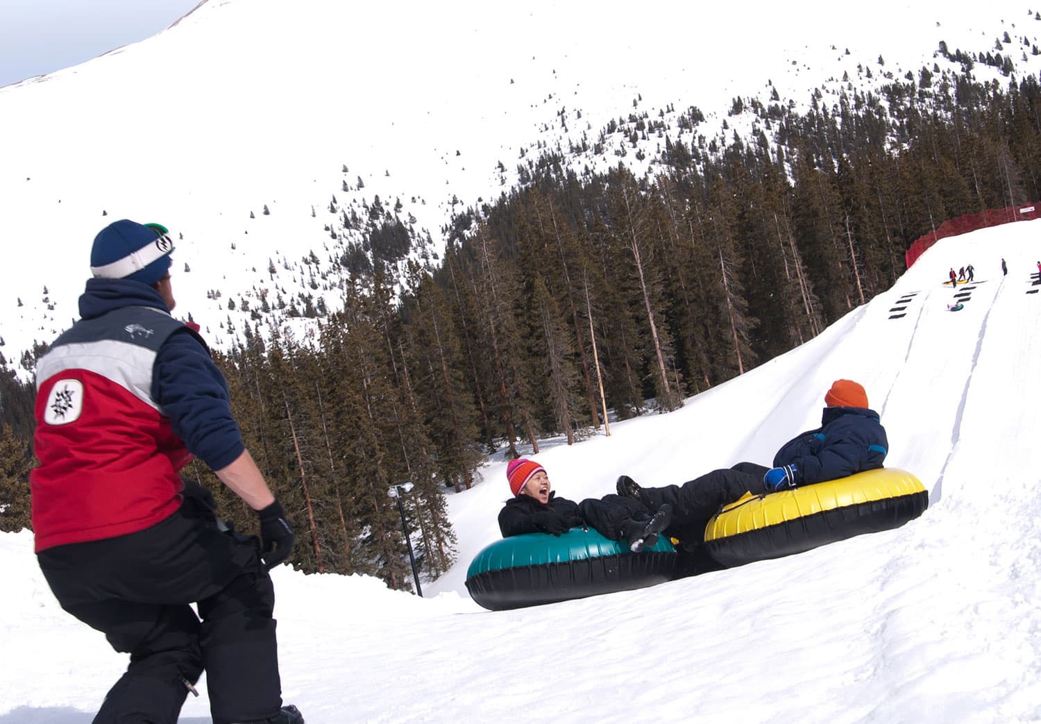A snow tube comes down the hill, where a person is watching the fun