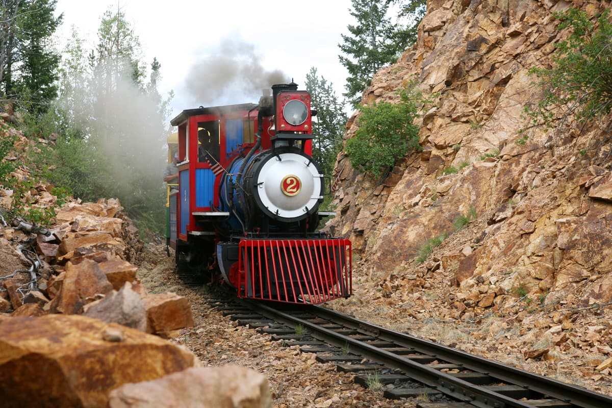 A red, blue and black train with the number two on the front travels down a railroad track between two rock walls in Colorado.