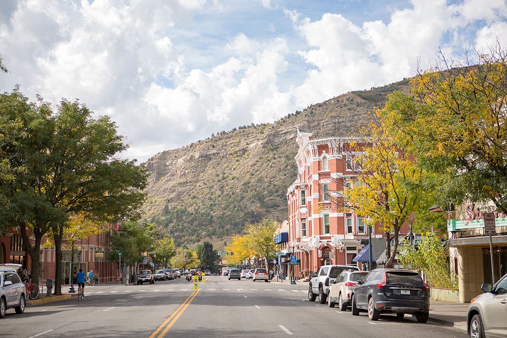 A street in Downtown Durango and the Historic Strater Hotel with a large hill in the backgroun