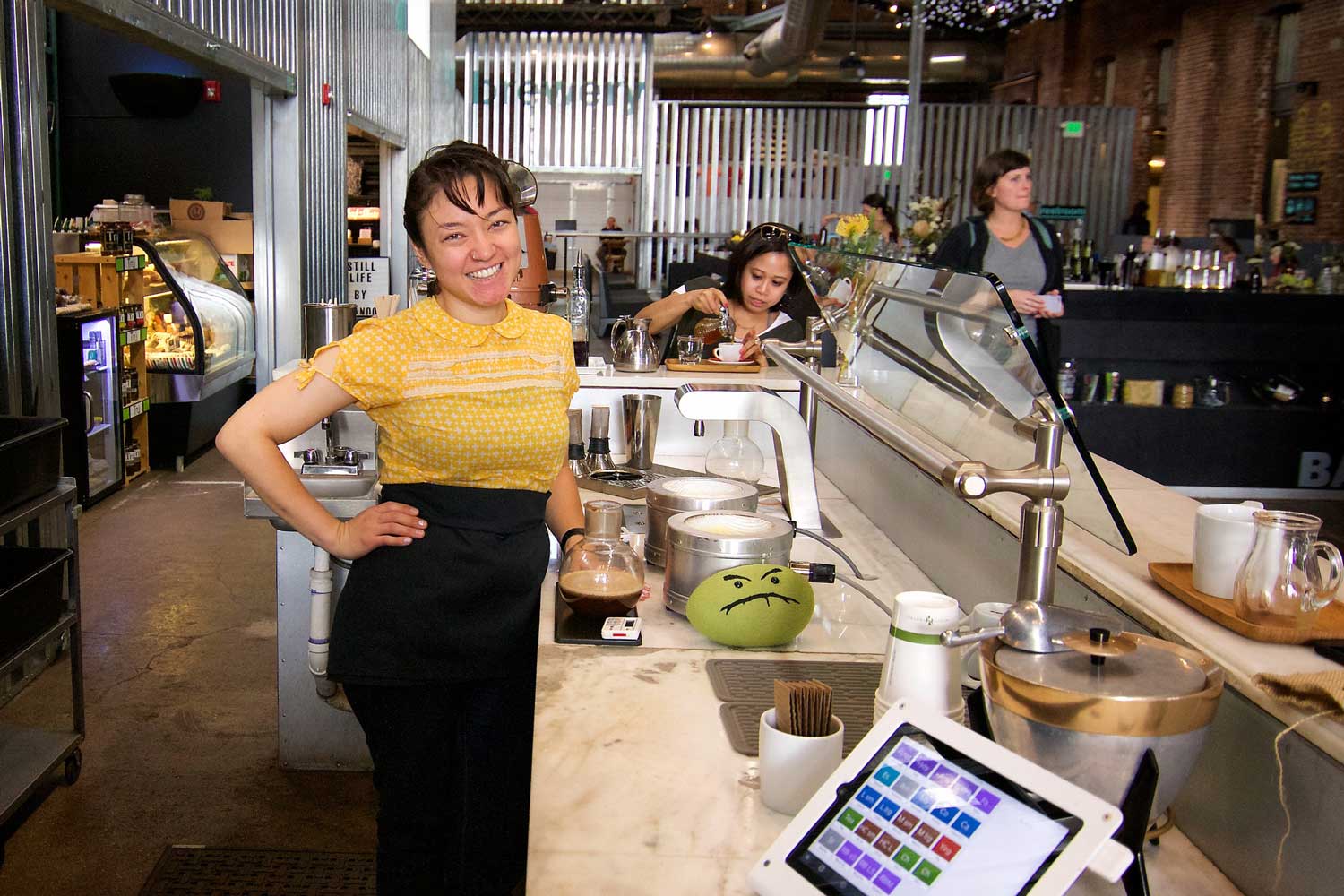 An employee smiles with hand on hop at Boxcar Coffee Roasters at The Source in Denver