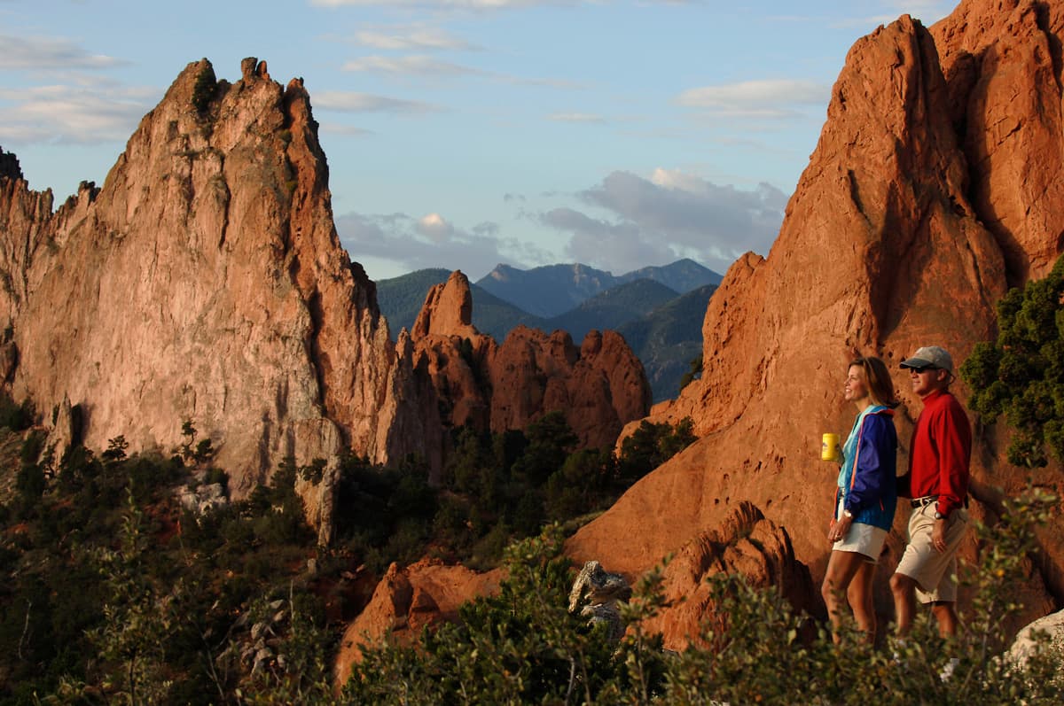 Two people pause to take in the views of the red rock formations at Garden of the Gods Park in Colorado.