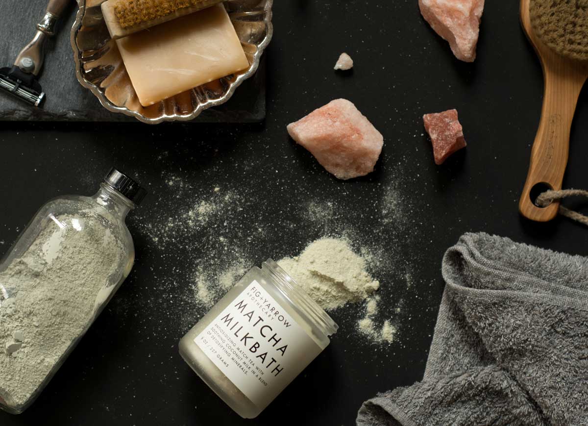Bath products and tools, including a gray towel and green matcha milkbath powder, somewhere in Colorado.