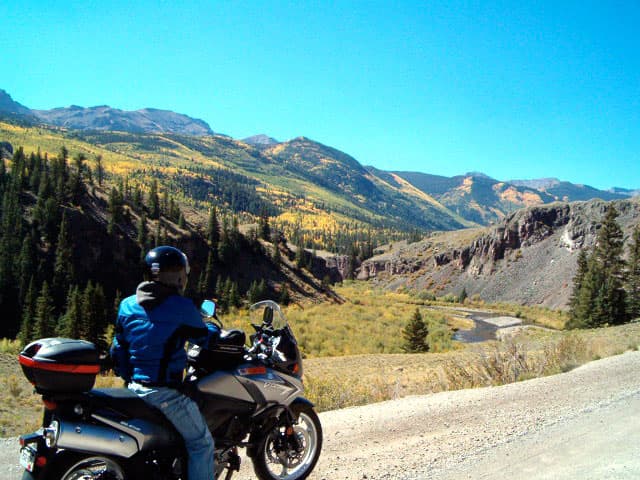 A motorcyclist pauses on the side of the road near Crested Butte, Colorado, to admire the sloping mountainside and fall foliage.