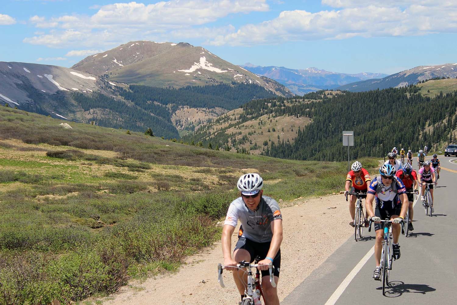 People road bike down a paved road with mountains in the background at Ride the Rockies bike race in Colorado