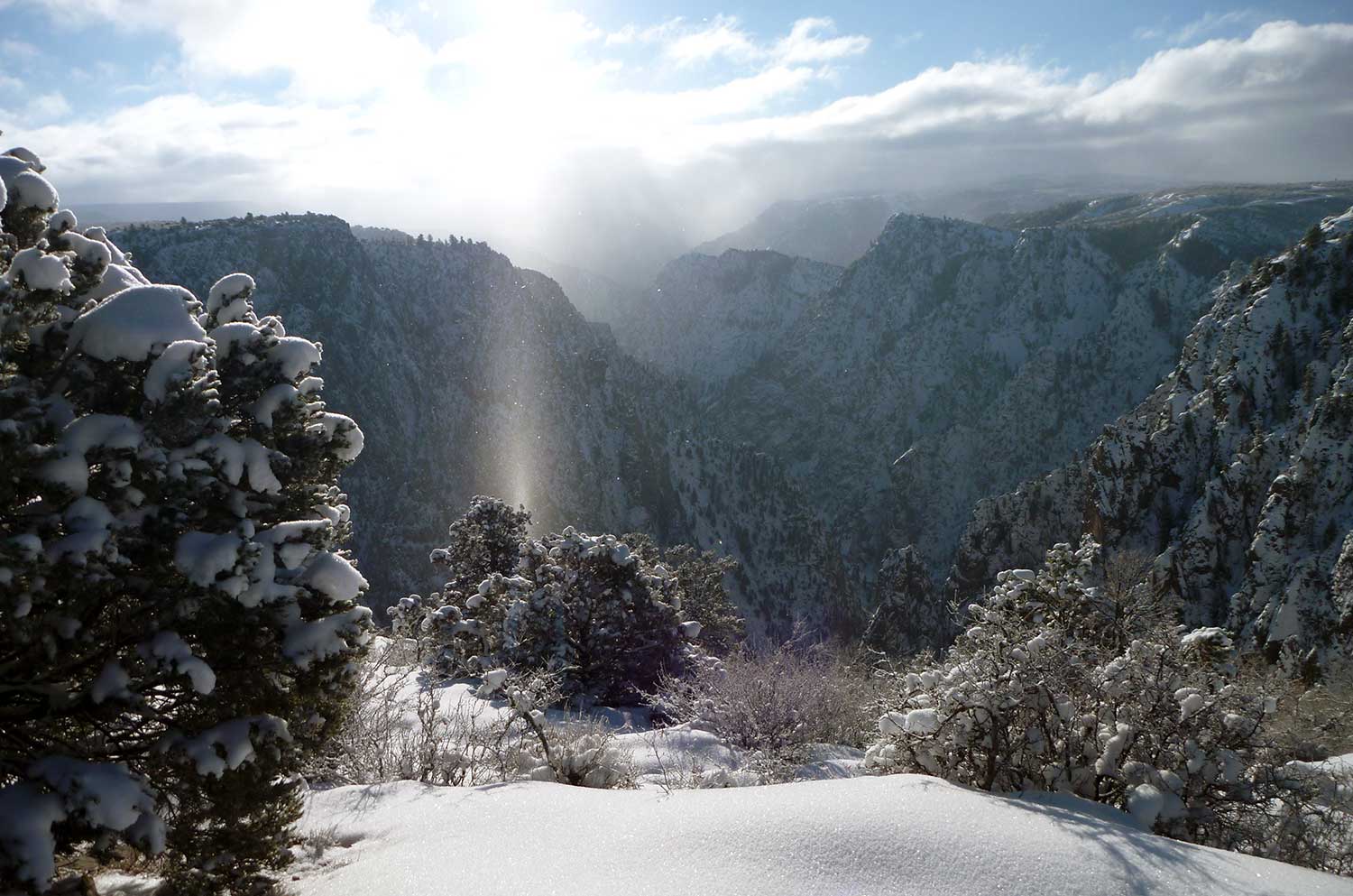 A sunbeam reflects down from the sky in a snowy mountain scene