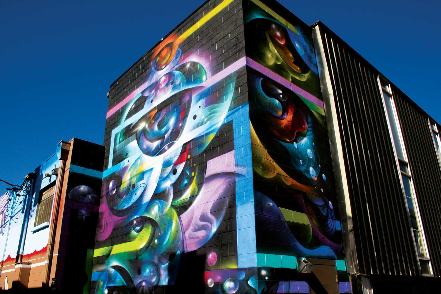 A large black brick building in RiNo is covered in neon colors and
