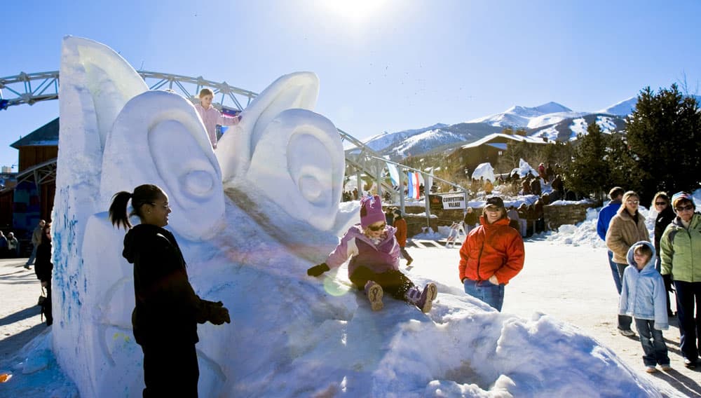 Kids play on the artworak at the Breckenridge Snow Sculpture Competition in Breckenridge, Colorado