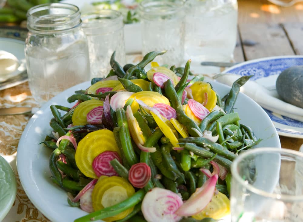 A white plate of fresh green, yellow and pink veggies