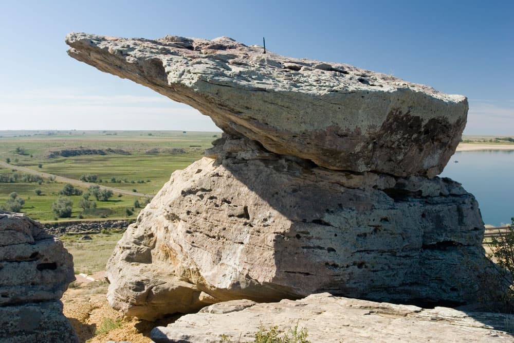 A grey slab of rocks is perched on the shore of the lake