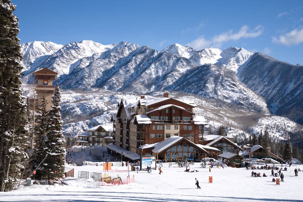 A snow-covered lodge at Purgatory Resort in Durango with snow-capped mountains in the background