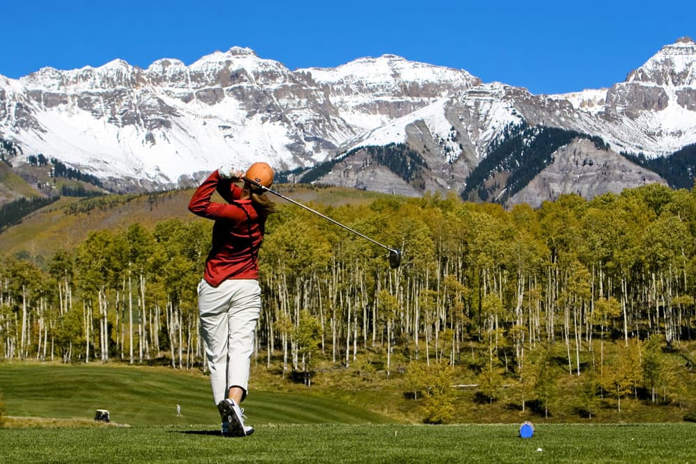 Golfer post swing with mountains in the background